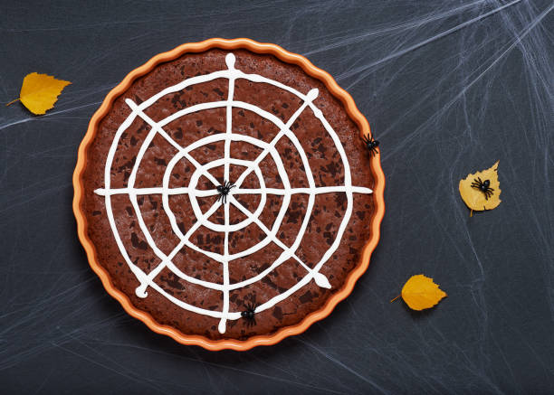 Halloween chocolate cake with spider web on a festive decorated table. Creative idea for treats. Top view.