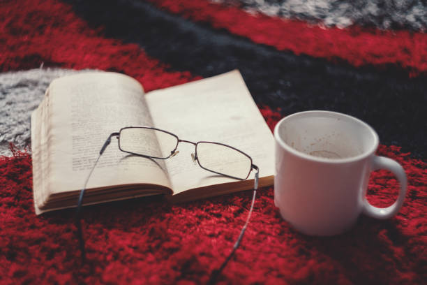istock Old Book With Reading Eyeglasses And Coffee On The Carpet - Vintage 1058337350