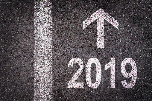2019 and an arrow written on an asphalt road background