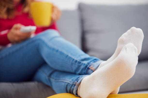 istock Girl holding TV remote and drinking coffee / tea on a couch. 1058347492