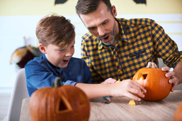 istock Father and son carving pumpkin 1058353230