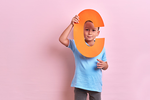 Studio portrait of child with cutout letters on pink background