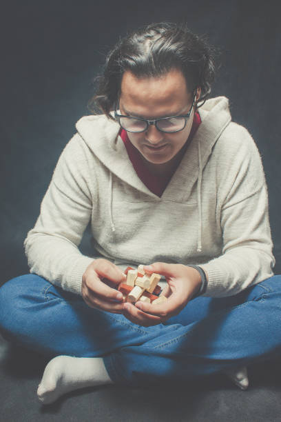 Smart guy with wooden puzzle sitting over dark background
