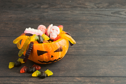 Trick or treat pumpkin jack with colorful candies on wooden background