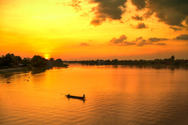 Silhouette fisherman on boat river sunset.