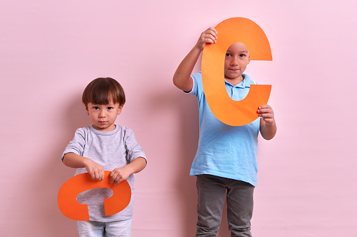 Studio portrait of kids with cutout letters on pink background