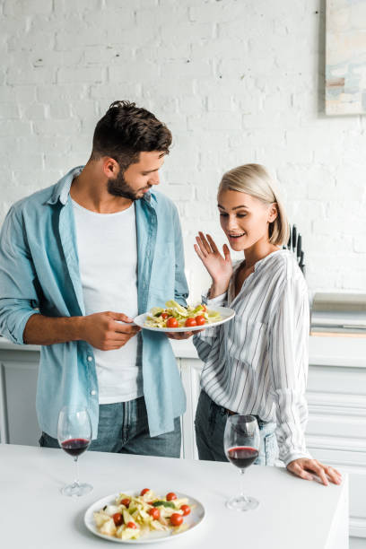 istock surprised girlfriend gesturing and looking at plate of salad in kitchen 1058360438
