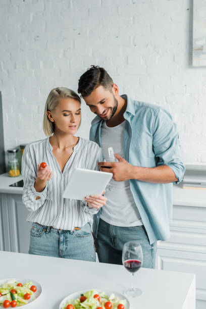 istock smiling young couple looking at tablet in kitchen 1058360552