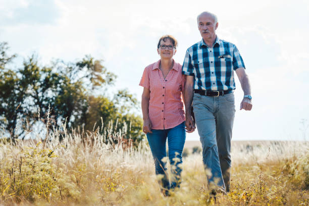 istock Senior couple walking over meadow holding each others hands 1058363380