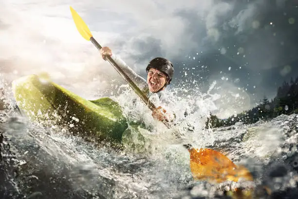 Whitewater kayaking, extreme kayaking. A fit woman in a kayak sails on a mountain river
