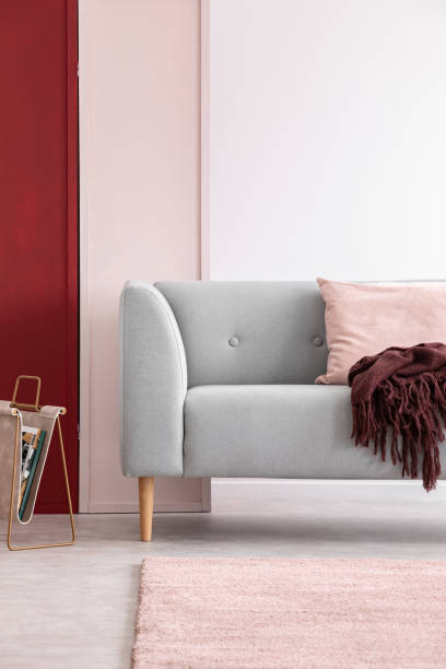 istock Newspaper rack next to grey couch in bright living room interior with three colored wall, real photo 1058369208