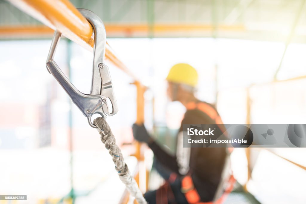 Industrial Worker with safety protective equipment loop hanging on the bar besides safety in factory concept for using in graphic media, websites, brochures, presentation in organization, etc. Falling Stock Photo