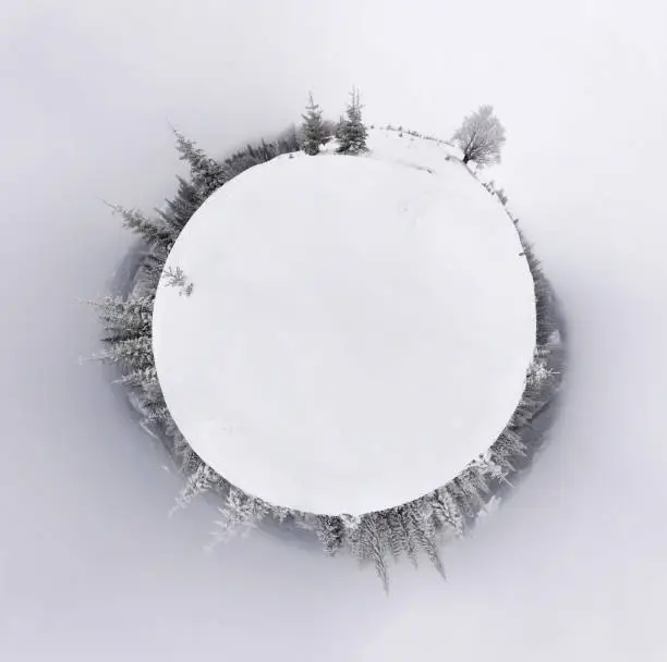 Photo of Little planet panorama of snowy hills montains landscape with forest.