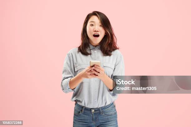 Young Beautiful Woman Using Mobile Phone Studio On Pink Color Background Stock Photo - Download Image Now