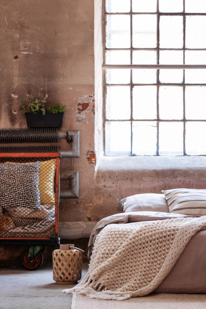 istock Lantern next to bed with blanket in bright loft bedroom interior with pillows and window. Real photo 1058375086