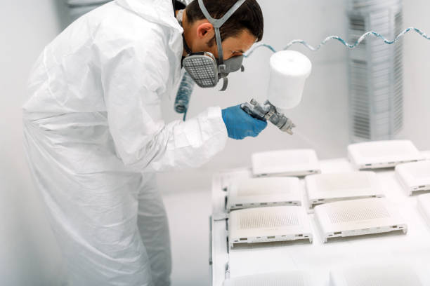 Painter using airbrush to paint wearing protective clothing