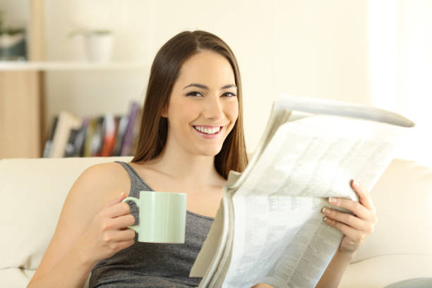 istock Woman holding newspaper and coffee cup looking at camera 1058384844