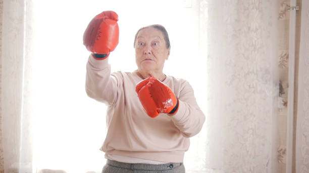 stare starsze kobiety boks w czerwonych rękawiczkach, patrząc agresywne i zabawne - senior adult 80 plus years aging process clothing zdjęcia i obrazy z banku zdjęć