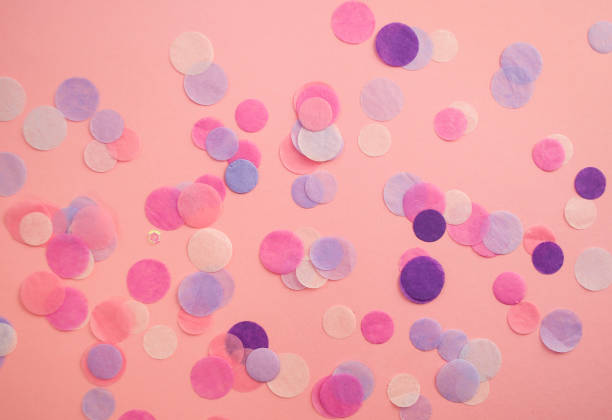 istock Multicolored confetti and sparkles on pink background. 1058390280