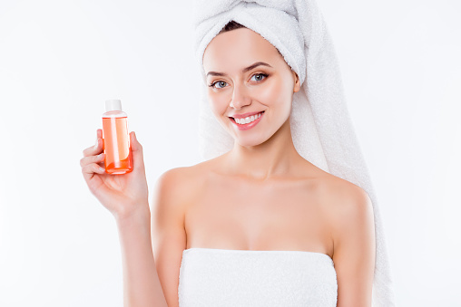 Portrait of pretty woman in towel and turban on head demonstrate lotion shower gel for dry body skin isolated on white background