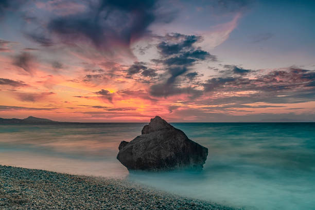Long exposure photograhy at the rocky Kato Petres Beach landscape at dusk. Rhodes, Greece