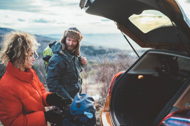 пара на походы принимая рюкзаки из багажника автомобиля - transportation mountain winter couple стоковые фото и изображения