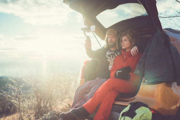 Young couple in the mountain drinking tea and vlogging for social media