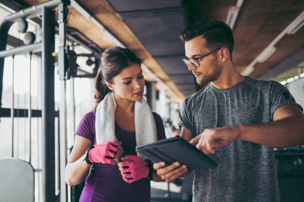 istock Young woman and personal trainer making exercise plan in gym 1058420056