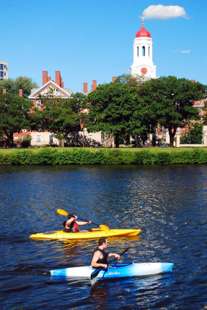 два каякера проходят мимо данстер хаус гарвардского университета - boston skyline architecture kayaking стоковые фото и изображения