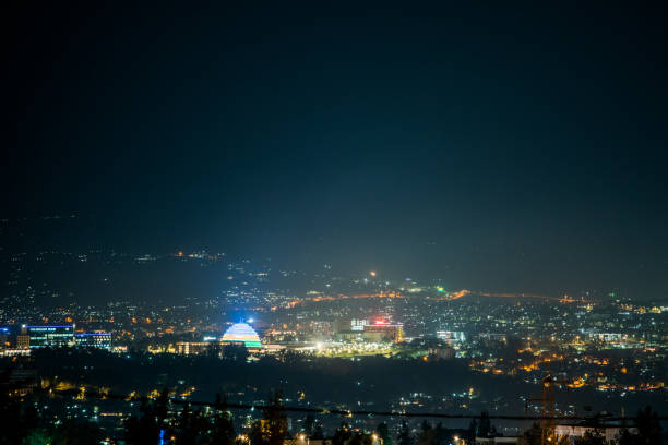 A wide view of city lights on the hills at night, with Kigali Convention Centre lit up in the colours of the Rwandan flag A wide view of city lights on the hills at night, with Kigali Convention Centre lit up in the colours of the Rwandan flag kigali convention center stock pictures, royalty-free photos & images