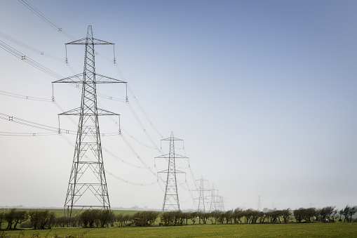 A line of electricity pylons in UK countryside. With blue sky and copy space