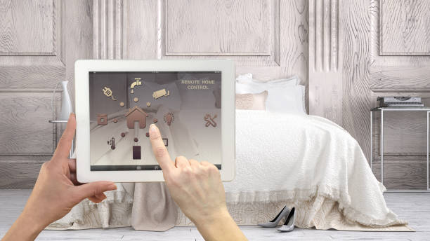 istock Smart remote home control system on a digital tablet. Device with app icons. Classic bedroom with double bed in the background, architecture interior design 1058443292