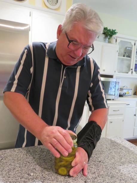 istock senior man in hand, wrist brace opening jar 1058443904