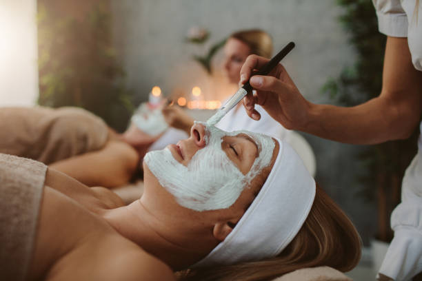 Mother and adult daughter enjoy beauty treatment in a spa center Beauty treatment. Beauticians applying facial mask on mature adult and senior women's face. spa lady stock pictures, royalty-free photos & images
