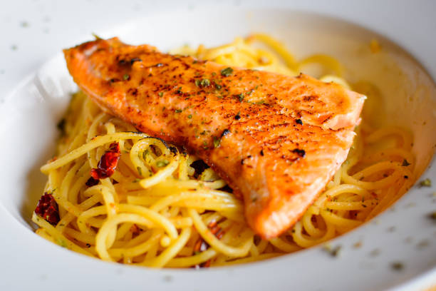Penne with grilled salmon and white wine on a table