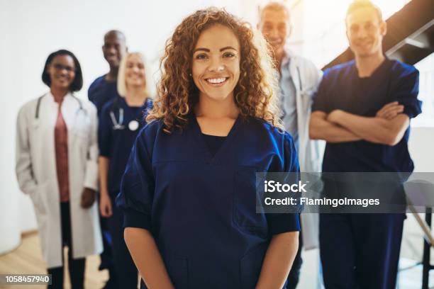 Smiling Female Doctor Standing With Medical Colleagues In A Hospital Stock Photo - Download Image Now