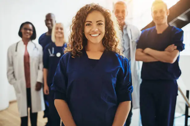 Photo of Smiling female doctor standing with medical colleagues in a hospital