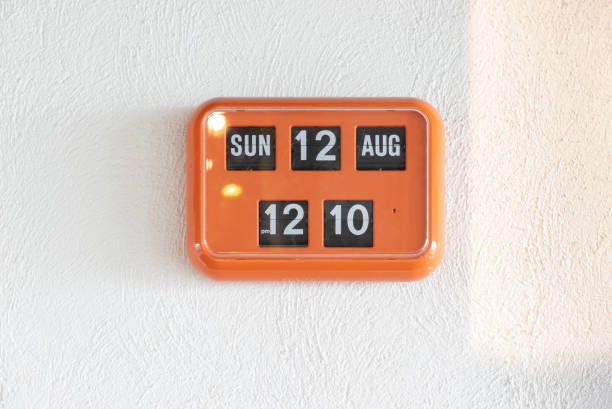 orange flip clock on white wall, retro analog timer. show time on 12 august at lunch time. orange flip clock on white wall, retro analog timer. show time on 12 august at lunch time. flip calendar stock pictures, royalty-free photos & images