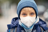 Little boy wearing pollution mask going to school
