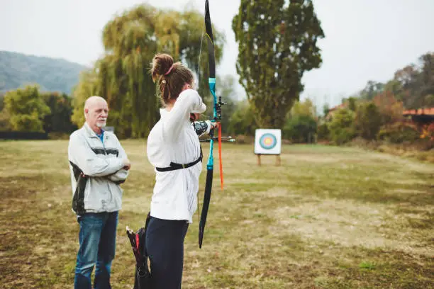 Teenage girl on archery training with her father as a coach.
