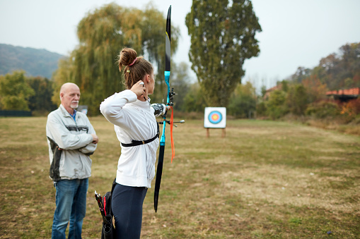 Teenage girl on archery training with her father as a coach.