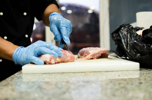 istock hands with gloves cutting raw meat 1058474202