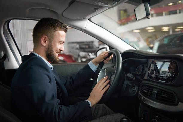 istock Man sitting in car holding hands on steering wheel. 1058476872