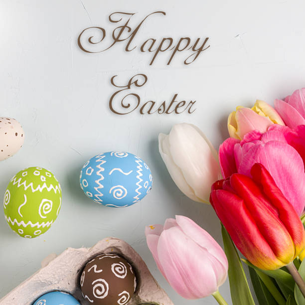 Painted easter eggs and bouquet of spring tulips closeup on a light blue background with space for congratulation