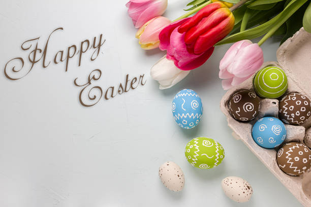 istock Painted easter eggs and bouquet of spring tulips closeup on a light blue background with space for congratulation 1058477956