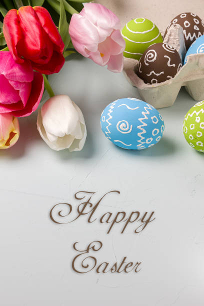 istock Painted easter eggs and bouquet of spring tulips closeup on a light blue background with space for congratulation 1058478418