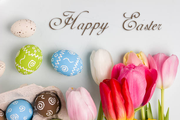 istock Painted easter eggs and bouquet of spring tulips closeup on a light blue background with space for congratulation 1058478726