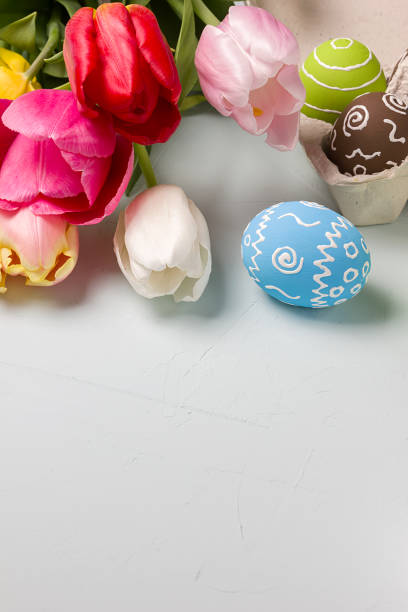 istock Painted easter eggs and bouquet of spring tulips closeup on a light blue background with space for congratulation 1058479032