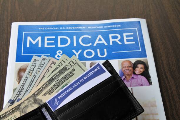 Medicare and Social Security cards with cash and Medicare handbook Medicare and Social Security cards with USA currency cash.  Cards and currency are protruding from an open wallet that lies on top of an official government printed Medicare Handbook. Health care and social welfare concept for seniors in the USA. social security social security card identity us currency stock pictures, royalty-free photos & images
