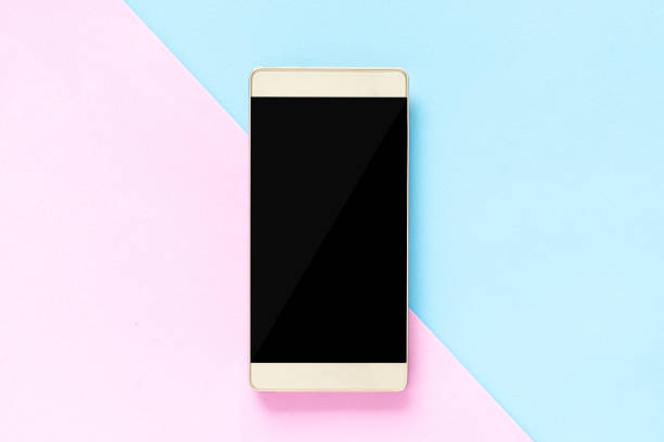 istock Mock up Flat lay smart phone on desk using phone black screen on top view, Background in pastel colors pink and blue 1058487094